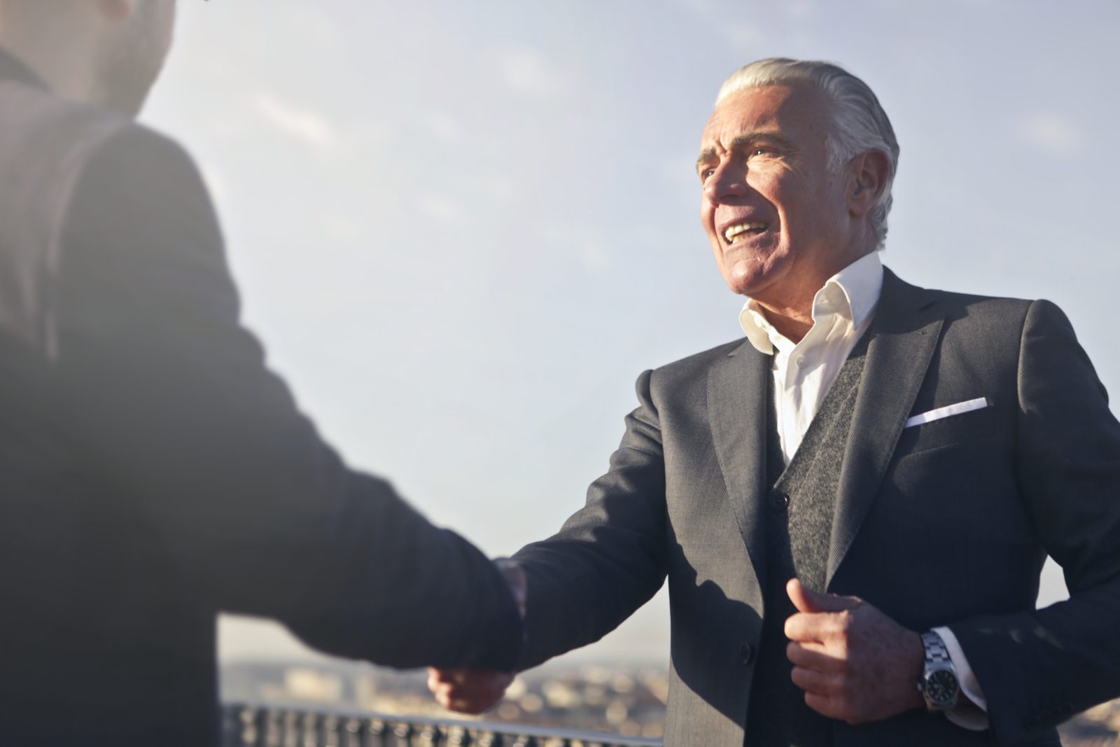 a man in black suite shaking hand