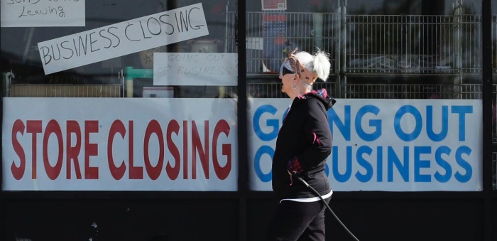 A woman in front of a store closing sign during the coronavirus pandemic